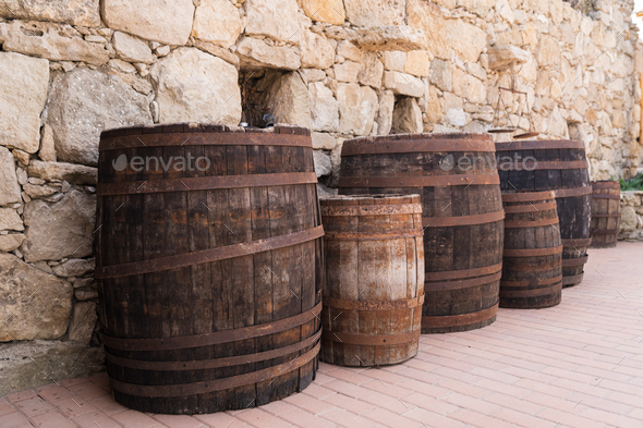 Old wooden barrels on stones wall texture background - Stock Photo - Images