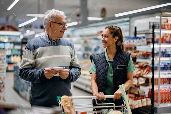 Happy senior man talking to supermarket manager while buying groceries.