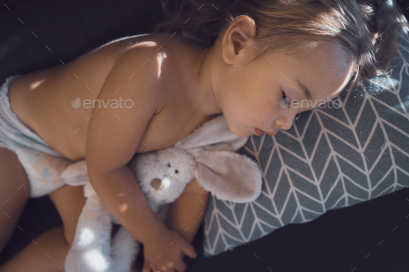Pretty baby hugs bunny and sleeping - Stock Photo - Images