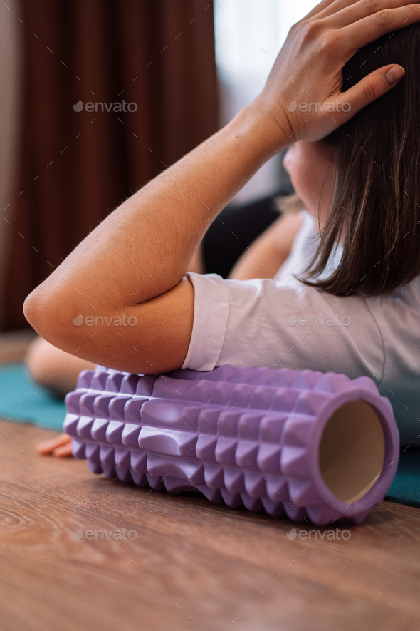 Lady kneads her arm muscles with a purple massage roller