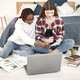 Two young teenage girls sitting on a floor near bed studying and using a laptop - PhotoDune Item for Sale