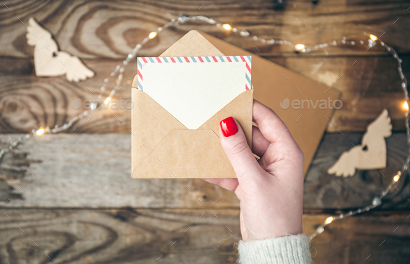 Blank postcard and envelope in female hands on a blurred wooden background. - Stock Photo - Images