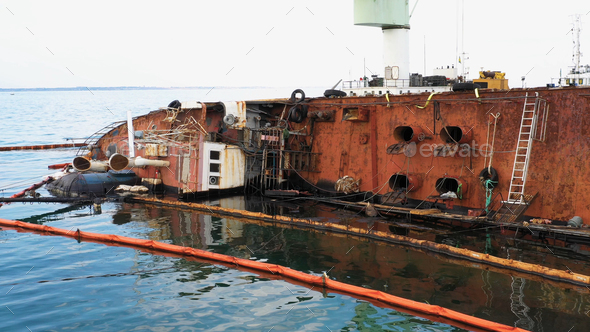 Close up of overturned oil tanker lying on its edge on the shallow water. - Stock Photo - Images