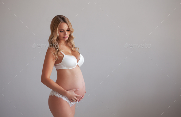 Beautiful fashion Pregnant woman in white underwear on gray background - Stock Photo - Images