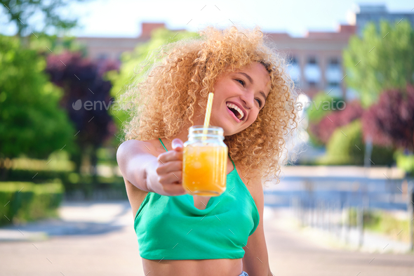 Young Brazilian woman laughing and holding a drink in a summer day. - Stock Photo - Images