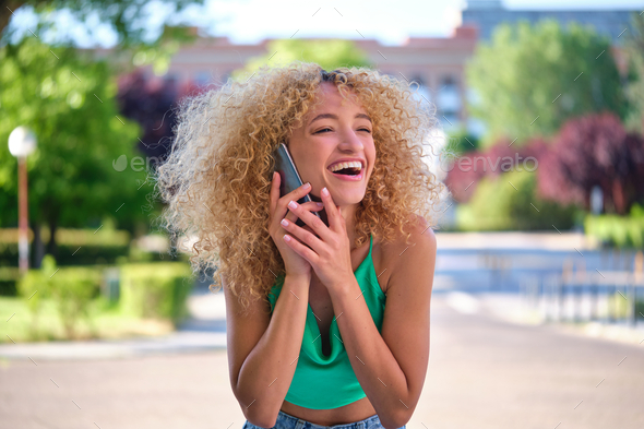 Young Brazilian woman speaking on the smartphone and laughing. - Stock Photo - Images