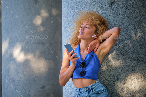 Young Brazilian woman wearing earphones listening music and singing. - Stock Photo - Images