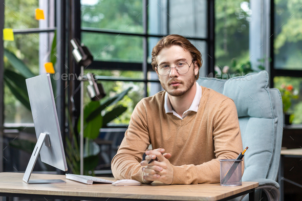 Portrait of thinking serious man with computer inside modern green loft office, blond man looking - Stock Photo - Images