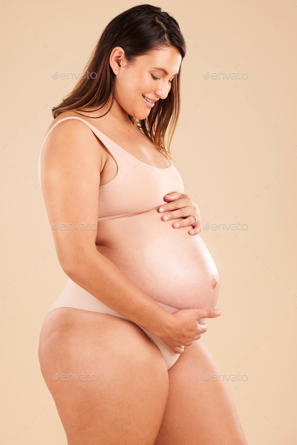 Shot Of A Beautiful Pregnant Woman Wearing Underwear And Holding