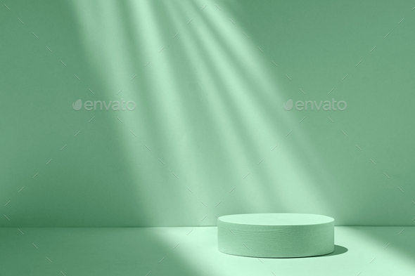 Podium cylinder in a beam of light on a green background with shadows and light to show the product - Stock Photo - Images