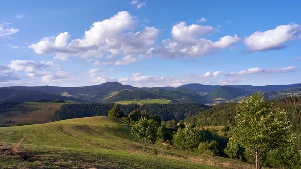 Rural landscape in the Carpathians with moving clouds in the blue sky alt