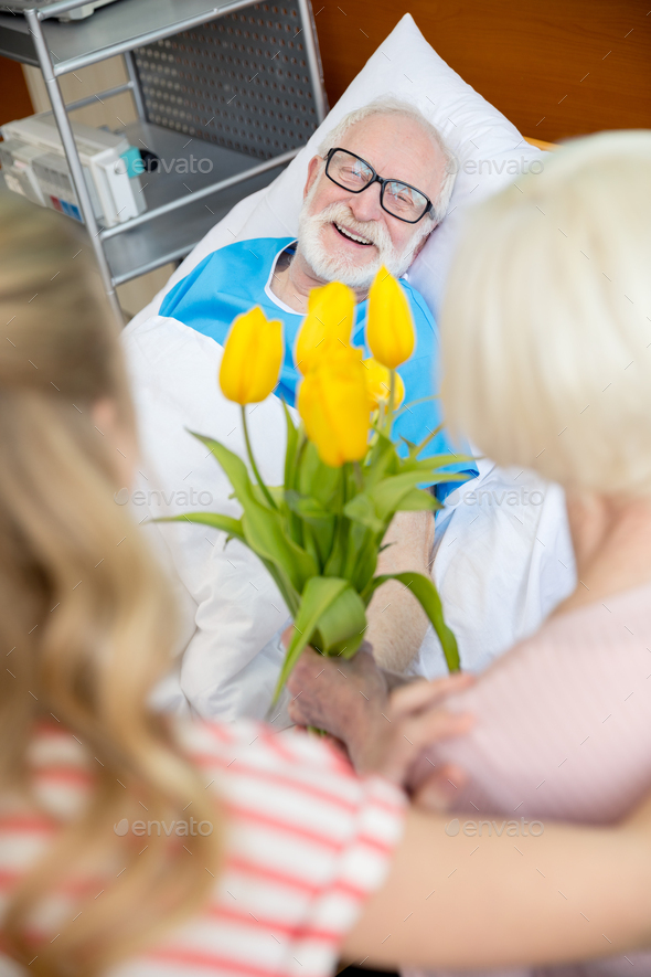 grandmother and granddaughter with tulip flowers visiting patient in