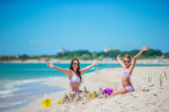 Mother and daughter enjoying time on the beach. Family making sand castle together on the seashore - Stock Photo - Images