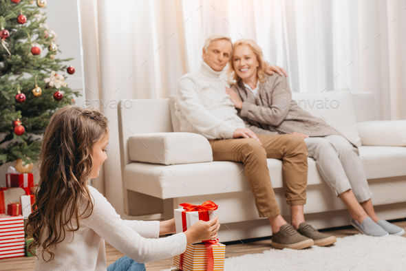 selective focus of happy grandparents and granddaughter with gift boxes sitting on floor - Stock Photo - Images