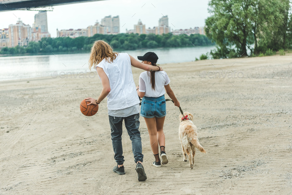 young couple on walk with dog on beach - Stock Photo - Images
