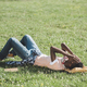 side view of african american student with hands on face resting on green grass in park - PhotoDune Item for Sale