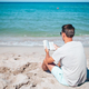Young man sitting on the beach reading book - PhotoDune Item for Sale