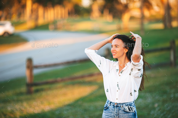 Portrait of happy young woman outdoor in the park at sunset - Stock Photo - Images