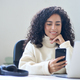 Young smiling latin business woman using phone in office sitting at desk. - PhotoDune Item for Sale