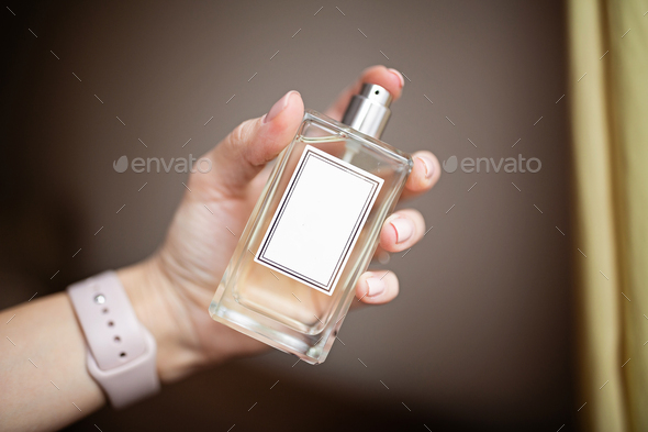 Woman hand holding bottle of perfume - Stock Photo - Images