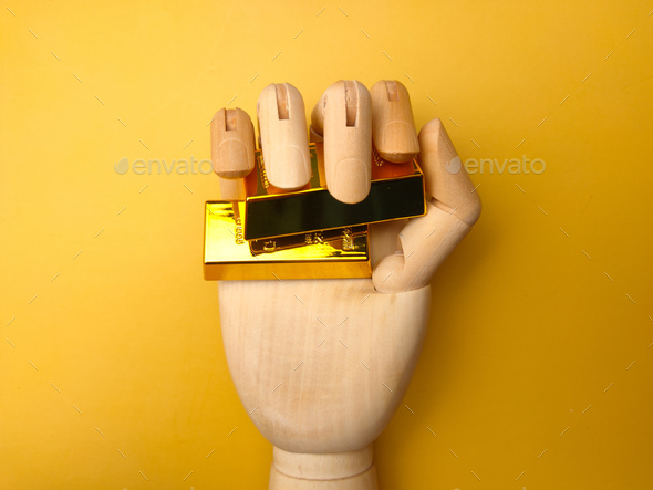 Wooden hand grab gold bar on a yellow background. Business concept. - Stock Photo - Images