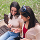 friends having fun on a park bench looking phone - PhotoDune Item for Sale