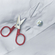 Needle thread scissors and button over white shirt - PhotoDune Item for Sale