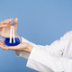 Asian scientist showing a glass container with blue liquid - PhotoDune Item for Sale