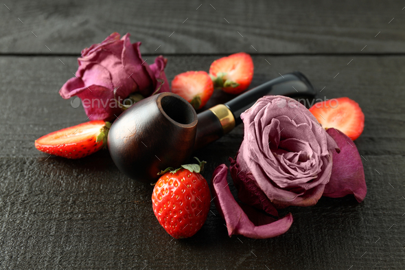 Roses, strawberry and smoking pipe on wooden background - Stock Photo - Images