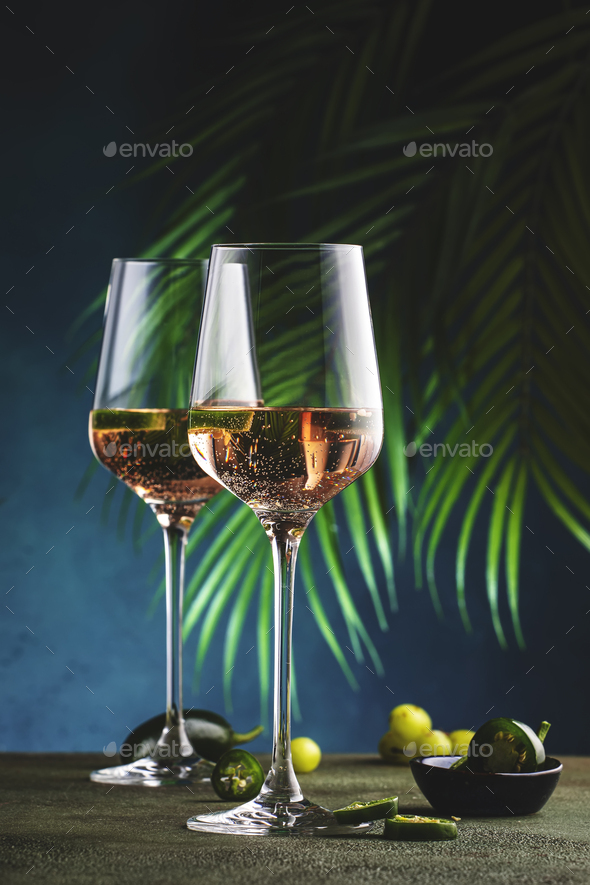 Rose wine with jalapeno pepper in wine glass, dark green background