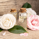 Camellia oil bottles and camellia flowers on rustic wooden table - PhotoDune Item for Sale