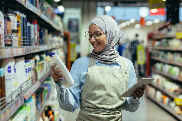 A young Arab woman in a hijab works in a supermarket, salesperson, consultant - Stock Photo - Images