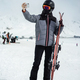 Girl dressed in a ski suit stands with ski against the backdrop of ski slope and take selfie - PhotoDune Item for Sale