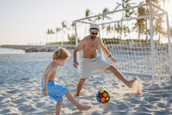 Father with his son plaing football on the beach. - Stock Photo - Images