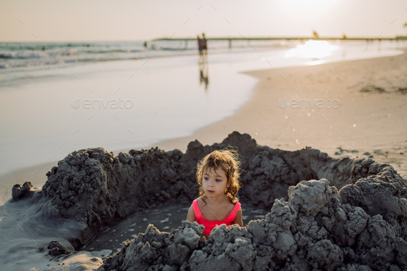 Little girl playing on the beach, digging hole in sand. - Stock Photo - Images