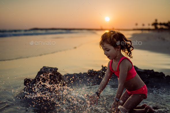 Little girl playing on the beach, digging hole in sand. - Stock Photo - Images