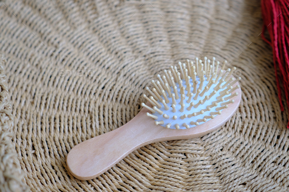 Small round wooden natural hair comb against the background of a wicker basket. Hair care.