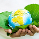 Little girl holding small planet in hands against spring or summer green background. Horizontal - PhotoDune Item for Sale