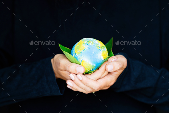 Young woman holding small planet in hands against black background. Ecology, environment and Earth - Stock Photo - Images