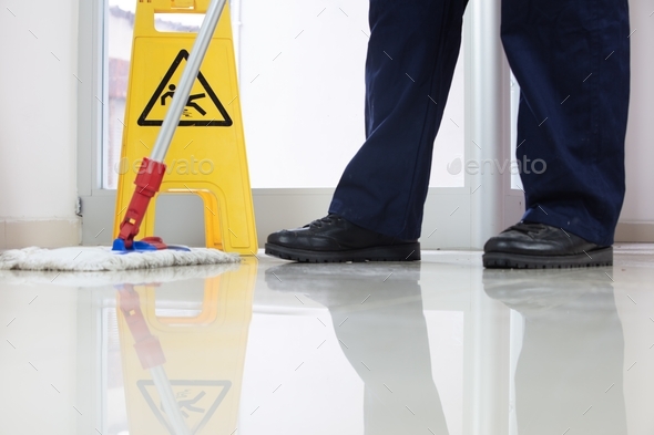 Man Cleaning Office With Mop Near Caution Wet Floor Sign Stock