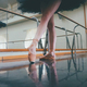 Ballerina in ballet pointe shoes stretches on barre. Woman practicing in  studio Stock Photo by Stock_Holm