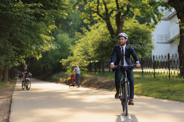 Happy male executive in business outfit returning from job on bicycle.  Stock Photo by tymoshchukph