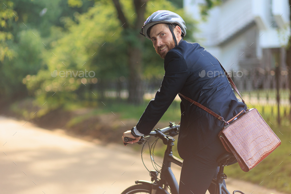 Smiling male entrepreneur in suit riding on bike to work.