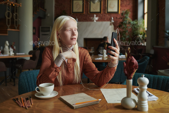 Young albino woman in casualwear talking to friend in video chat - Stock Photo - Images