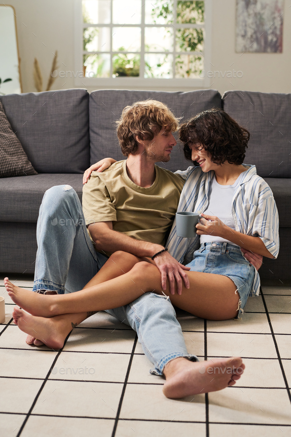 Happy young barefooted couple in casualwear relaxing on the floor - Stock Photo - Images