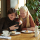 Two young cheerful girlfriends discussing online photo or video in mobile phone - PhotoDune Item for Sale