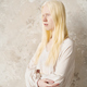 Young albino woman in white cotton casualwear standing by marble wall - PhotoDune Item for Sale
