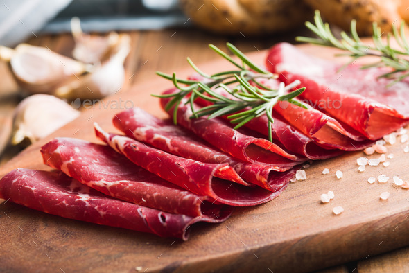 Smoked bresaola. Italian appetizer. Dried beef meat on cutting board. - Stock Photo - Images