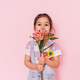 Little multi ethnic girl holding flowers against pink background, mother&#39;s day - PhotoDune Item for Sale