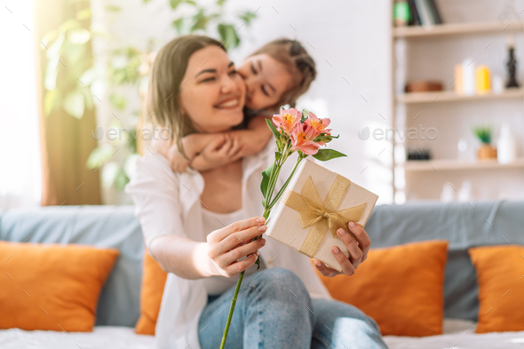 Daughter hugged her mother and gave a gift and flowers, mother's day - Stock Photo - Images